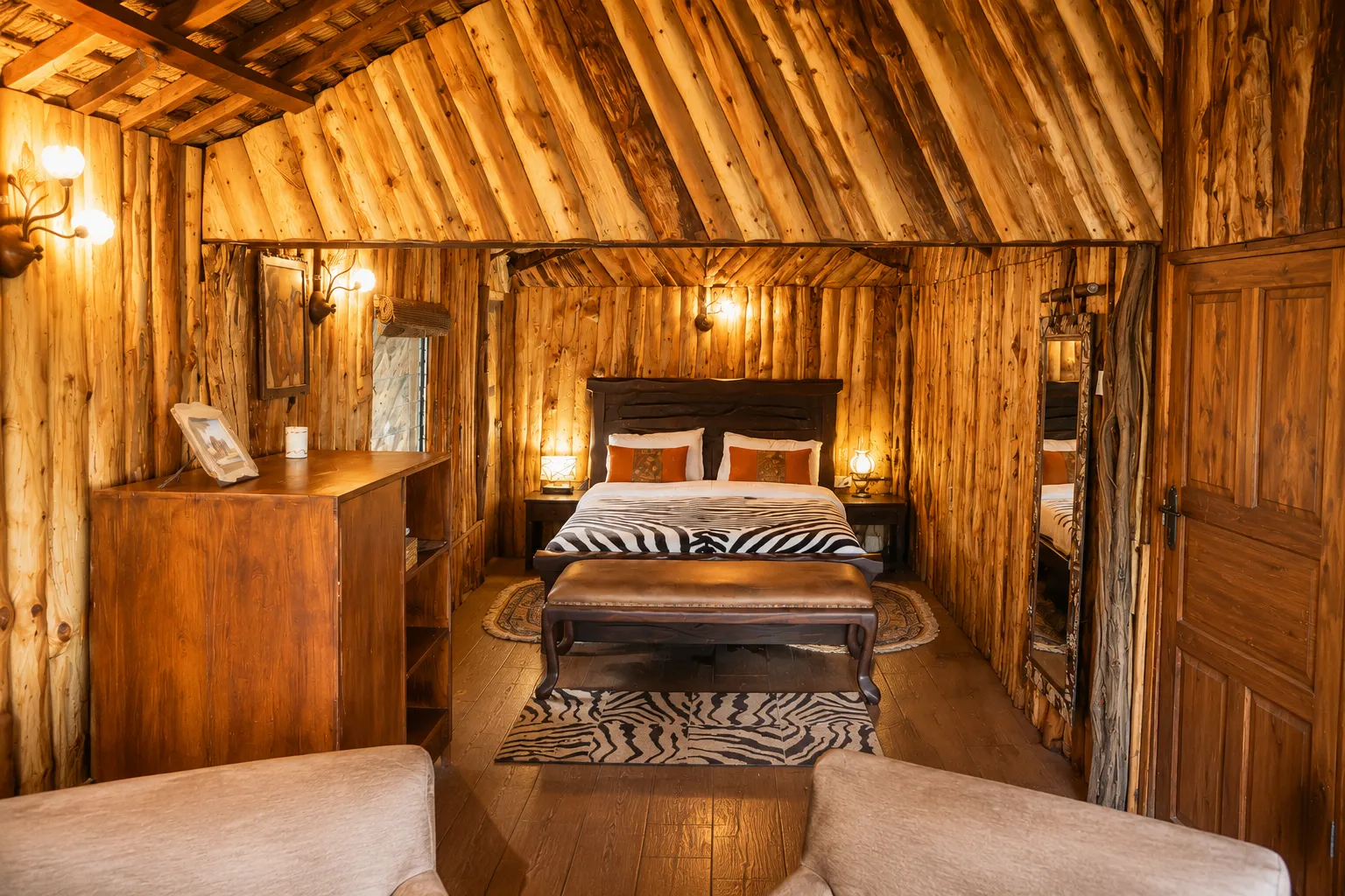 Comfortable master bedroom with a king-size bed and authentic African decor inside Simba's Den cabin in Masai Mara